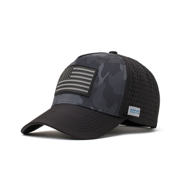 Angled view of a black performance hat showcasing a dark camo design, black flag logo patch, and a curved brim for added style and functionality