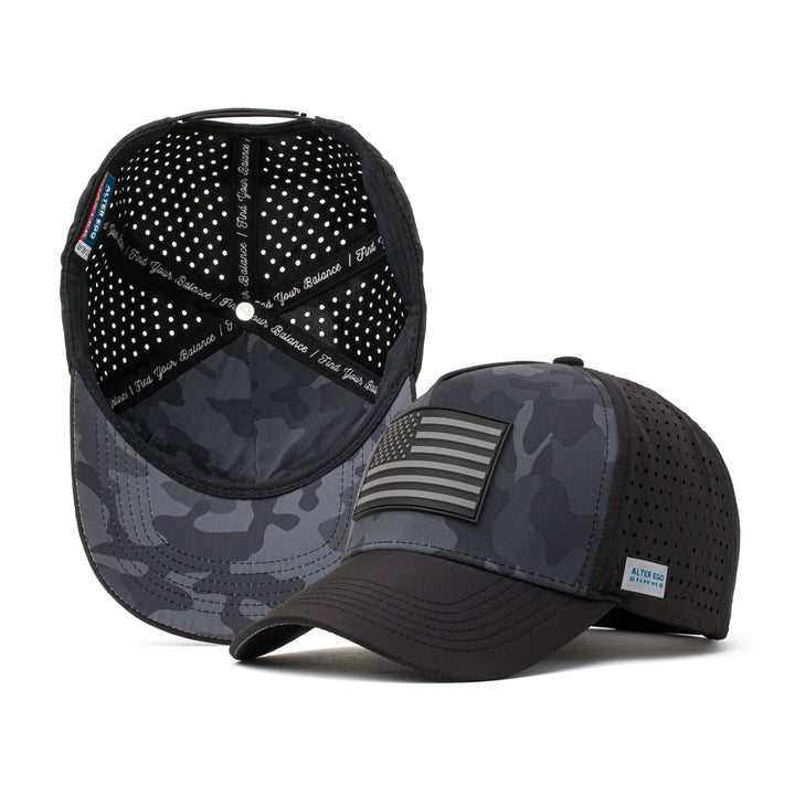 Black performance hat with a dark camo design and a black American flag patch on the front, paired with a breathable perforated mesh back for outdoor and athletic activities.