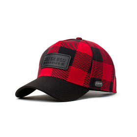 Angled front view of a red and black buffalo plaid insulated hat featuring a black leather patch logo, curved brim, and thermal interior for style and functionality in cold weather.