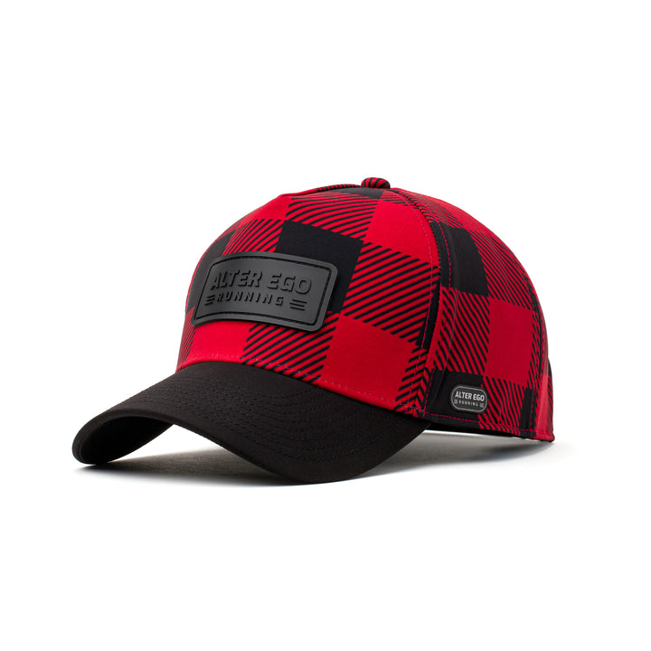 Angled front view of a red and black buffalo plaid insulated hat featuring a black leather patch logo, curved brim, and thermal interior for style and functionality in cold weather.