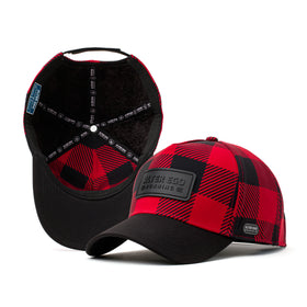 Red and black buffalo plaid performance hat with a black leather patch logo on the front and insulated interior, designed for cold weather comfort.