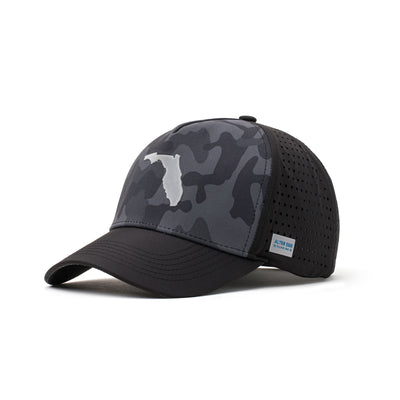 Angled view of a black performance hat showcasing a dark camo design, black flag logo patch, and a curved brim for added style and functionality.