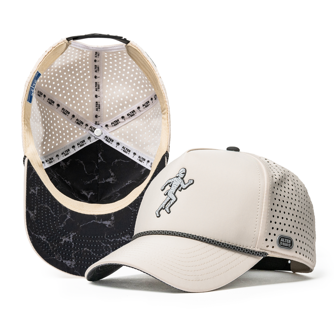 Alter Ego Coaster Splash Ivory Mummy hat featuring an ivory crown, curved bill with a black marble-inspired underbill design, embroidered running mummy graphic, laser-cut ventilation, and a reflective Alter Ego side badge.