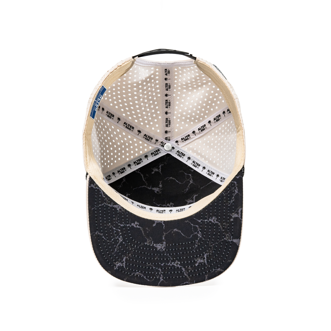 Inside view of the Drifter Splash Ivory Mummy hat showing the ivory interior, Alter Ego branded seam tape, perforated panels, and black marble-patterned flat bill.