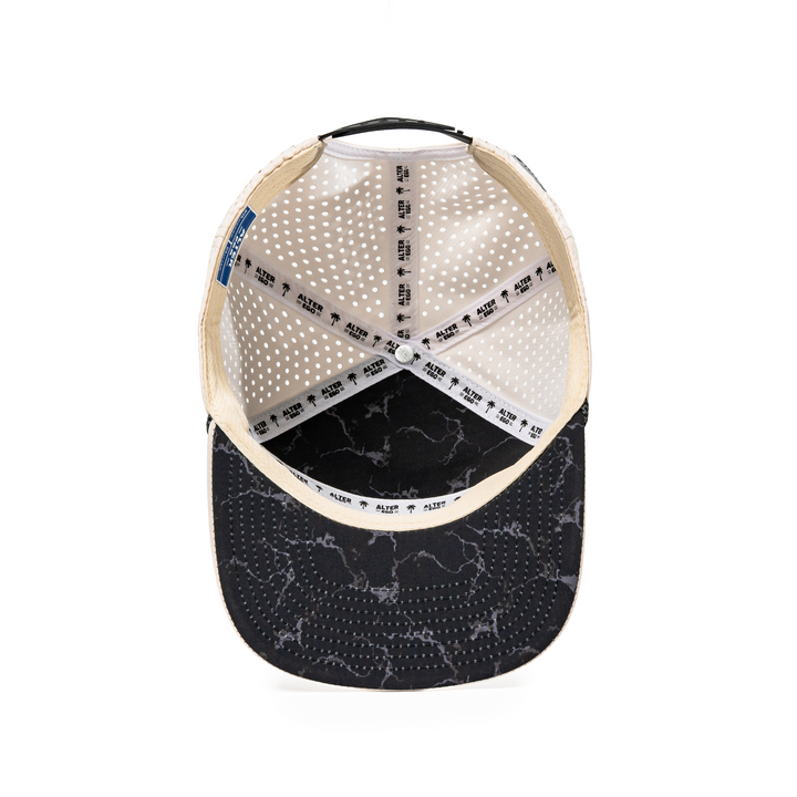 Inside view of the Drifter Splash Ivory Mummy hat showing the ivory interior, Alter Ego branded seam tape, perforated panels, and black marble-patterned flat bill.